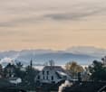 row of houses in a town with mountains in the background, clear skies, chimneys visible