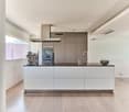 Spacious modern kitchen with white cabinets, black countertops, built-in appliances including a dishwasher, and a coffee machine on the counter.