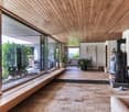 large glass windows, wooden ceiling, wood flooring, large glass doors, living area, fireplace