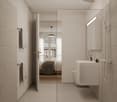 white tiled walls, glass doors, ceiling mounted shower, white sink, wall-mounted toilet, bed in adjacent room
