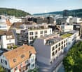 Modern apartment building with multiple floors, green roofs, balconies, and terraces.