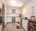 white cupboards, tile floor, countertop, sink, coffee machine, faucet, wine rack