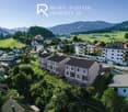 Newly built residential complex, modern design, gray roofs, raised ground floor, balconies, surrounded by greenery