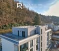 Modern apartment building, white exterior, large windows, multiple balconies, raised ground floor