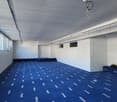 empty room with blue carpet and white walls, ceiling with track lighting, windows, and doors