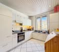 white kitchen, white tiled floor, white upper and lower cabinets, oven, refrigerator, sink, open window, fruit bowl on countertop