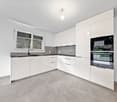 white cabinets, black countertops, silver stove and oven, white sink, faucet