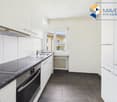 modern kitchen, white cabinets, black countertops, induction stove, oven, sink, window, radiator