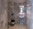 Tiled bathroom with a toilet, sink, and washing machine