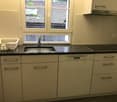 white cabinets, granite countertop, stainless steel sink, dishwasher, black stovetop