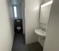 White walled bathroom, black tiled floor, sink, mirror, toilet, natural light
