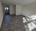 Empty room with tiled floor, white walls, window, open hallway