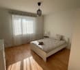 Bedroom with bed, nightstand, lamp, closet, and window with curtains.