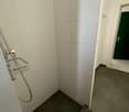 empty shower with gray floor, white walls and tiled floor
