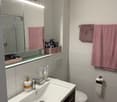 white tiles, white sink, pink towels, mirror, toothbrush, toilet, toilet paper