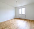 empty room with white walls, wooden floor, radiator under window, double window