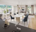 Open plan living and dining area with large windows, balcony, modern furniture, kitchen island, and a view of the mountains.