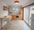 orange cabinets, white tiles, open sliding door leading to a patio