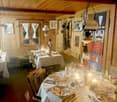 Rustic wooden interior with exposed beams, dining table set with plates and glassware, candles, and a nutcracker figure on display