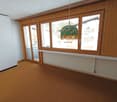 empty room with windows, a white radiator, brown carpet, wooden walls, sliding doors