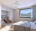 wooden floor, desk with TV, chair, double bed, bedside tables, large window with curtain