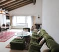 green couch, coffee table, dining table, chairs, fireplace, wooden ceiling