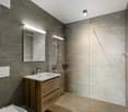 modern style bathroom, white tiles, sink with wooden cabinet, glass shower, white light fixtures