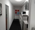 Empty hallway with white walls, black carpet, ceiling light, cabinets, and a poster