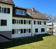 3 story house, white walls, brown roof, multiple windows, green lawn