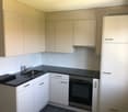 modern kitchen with white cabinets, black countertops, stainless steel sink, oven, and dishwasher