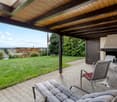 Fireplace, outdoor seating, covered patio, brick paving, lush green lawn, view of the horizon