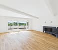Wooden floors, white walls, large windows with open sliding doors, balcony with railings, fireplace, no furniture