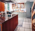 modern kitchen with wooden cabinets, granite countertop, gas stove, refrigerator, sink, wooden stairs
