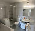 white bathtub, glass shower, white toilet, sink, mirror, white washing machine