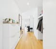 corridor with wooden floor, white walls, cabinet, potted plants, mirror, wardrobe