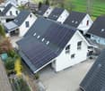 Detached houses with solar panels on the roof, driveway, garden, green fields in the background