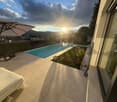 Outdoor area with swimming pool, tiled floor, umbrella, plants, and a view of the city