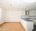 Empty kitchen with white cabinets, wooden floor, granite countertop, stainless steel range hood, white ceiling with recessed lighting, large window