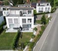Modern two-story house with solar panels, balconies, and a garden with a terrace.