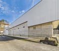 large concrete wall, white roof, concrete base, large driveway, white exterior