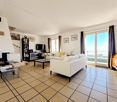 white sofa, coffee table, TV, bookshelves, tiled floor, sliding glass door, balcony