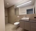Bathroom with modern design, large mirror, white toilet, white sink, tiled floor, shower area