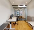 Office: white walls, wooden floors, glass walls, adjustable height desk, chair, computer