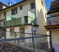 3 story house, white walls, green balconies, chain link fence in the front