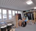 room with large windows, ceiling lights, boxes, cables, tires, shelves
