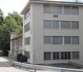 Office building, 4 floors, white exterior, large windows, parking lot in front