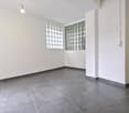 Empty room with white walls, gray tiles, two glass block windows, and ceiling lights