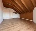 empty attic room with wooden walls, wooden beams ceiling, wooden floor