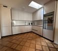 modern kitchen, white cabinets, wooden floor, stainless steel appliances, skylight