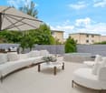 Outdoor patio area with couches, coffee table, hot tub, umbrella, plants, and fences.